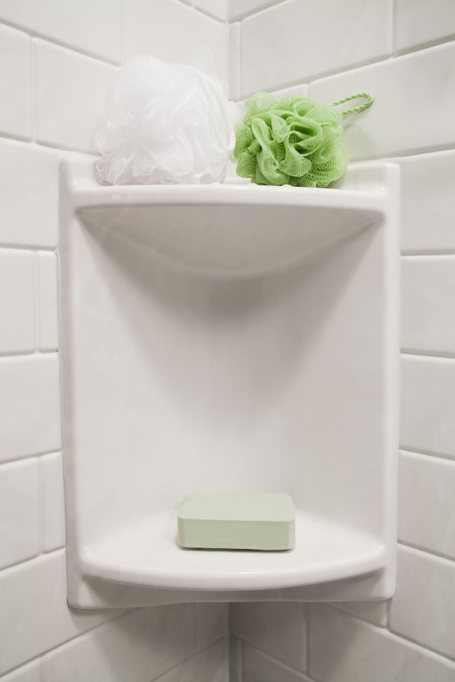 Two-shelf corner caddy with white subway tile walls